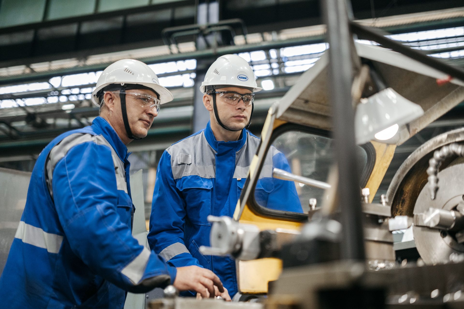 Deux opérateurs casqués contrôlent une machine dans une usine