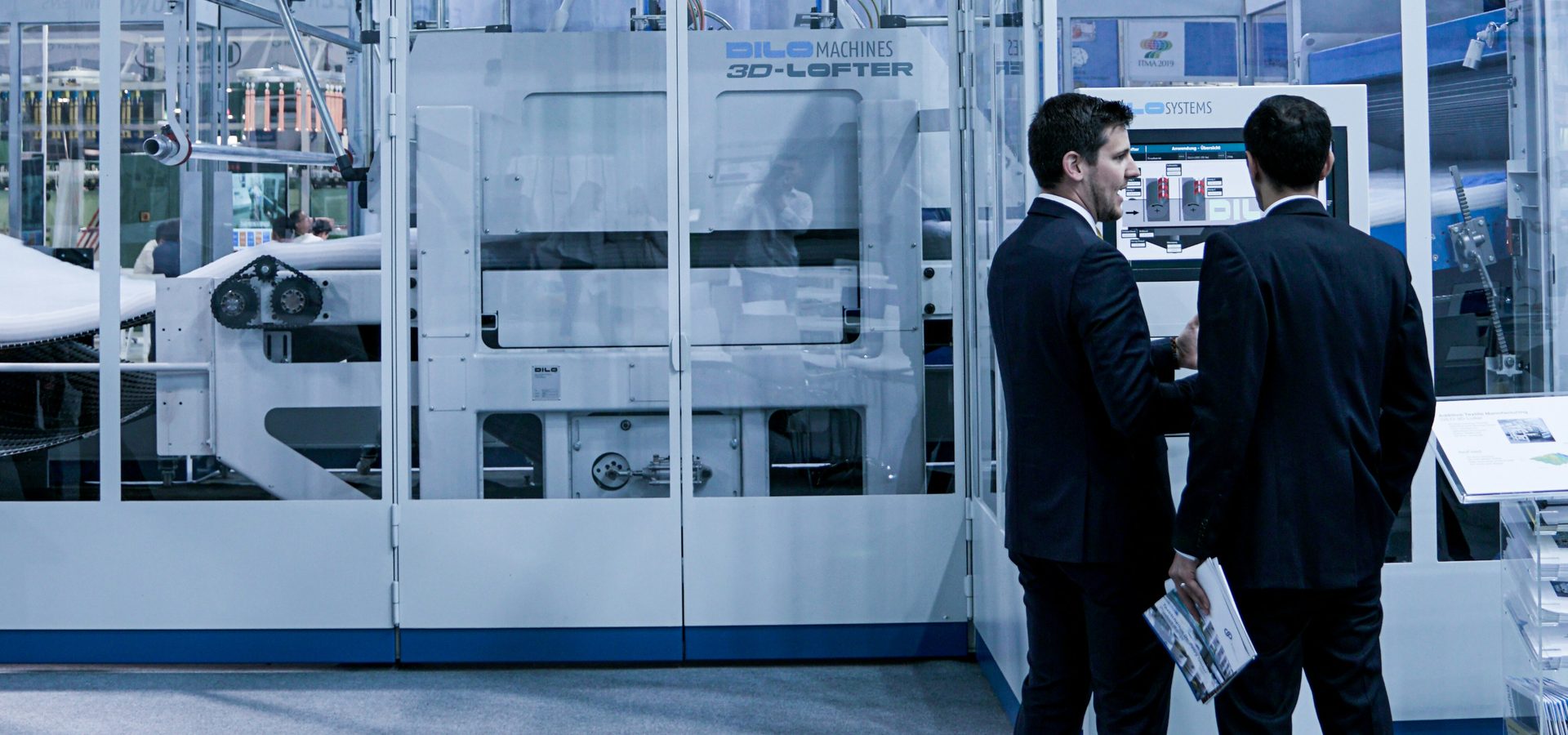 Deux dirigeants en costume devant une ligne de production automatisée